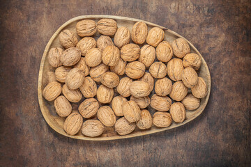 Walnuts on dark vintage table top view. Fresh Walnuts kernels in wooden plate. Copyspace