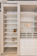 Wardrobe with many shelves, on which are two pairs of women's shoes and four-dimensional letters 