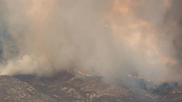 Air tanker DC-10 flies through dark smoke of the Fairview fire along the fires edge in Hemet, California