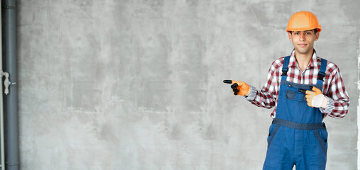 Naklejka premium Young arabic man over grey wall wearing contractor uniform and safety helmet happy with smile showing with thumb up to the side with happy face smiling.