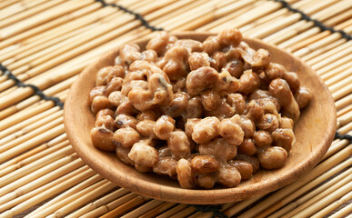Natto or Fermented Soybean in wood plate on bamboo mat background. Natto or Fermented Soybean...