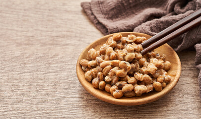 Natto or Fermented Soybean in wood plate and chopsticks on wooden table background. Natto or...