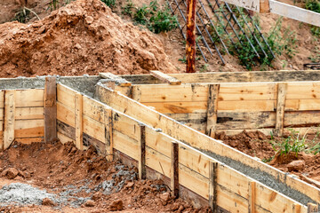 Reinforced concrete foundation of a modern monolithic residential building. Prepared formwork with reinforcing mesh for pouring concrete. Dirt and clay at the construction site.