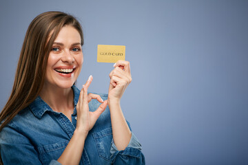 Smiling woman in blue casual shirt holding credit card. isolated close up portrait on blue.