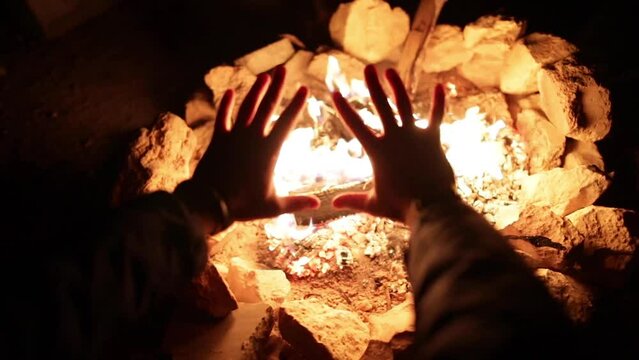 man warming hands by cozy bonfire during cold winter in Europe, zoom out