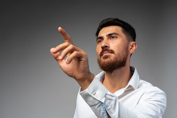 Young Arab businessman working with virtual screen over grey background.
