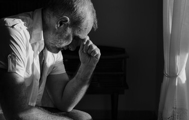 Portrait of adult man sitting on bed against window with sunlight and shadow