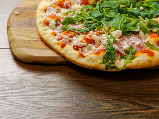 Top quality uncooked Italian pizza with spinach and meat on a wooden tray and table. Cook at home product. Top range ingredients. Classic meal.