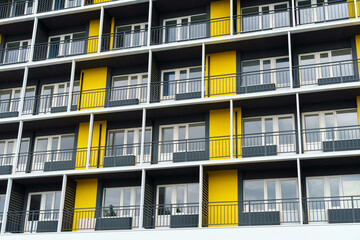 the facade of a modern multi-storey building, windows and balconies, yellow and black walls, the concept of urbanism and city construction