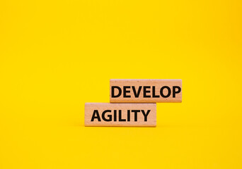 Develop agility symbol. Concept word Develop agility on wooden blocks. Beautiful yellow background. Business and Develop agility concept. Copy space