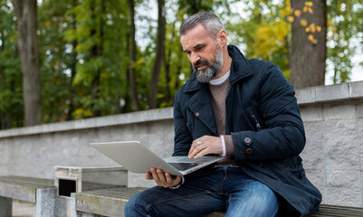 Obraz premium businessman working online on laptop in city park