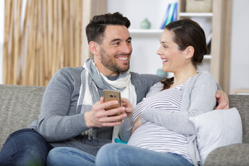 happy man and pregnant wife with smartphone at home