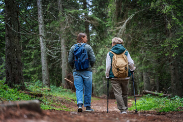 Two adult women girlfriends mother and daughter walking in the autumn rainy forest, outdoor activities and enjoying nature