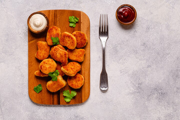 Fried crispy chicken nuggets on a wooden serving board.