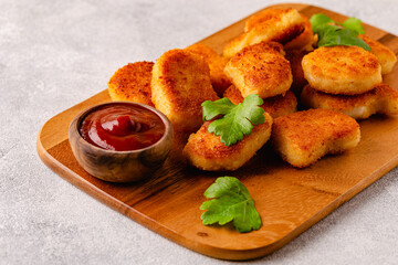 Fried crispy chicken nuggets on a wooden serving board.