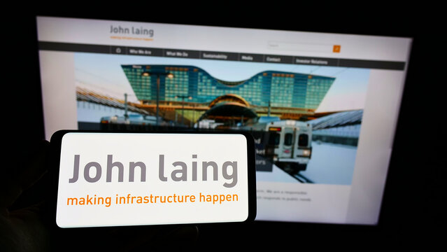 Stuttgart, Germany - 12-12-2021: Person holding smartphone with logo of British company John Laing Group Limited on screen in front of website. Focus on phone display.