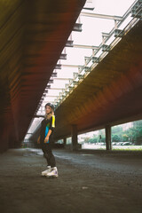 Young adult urban woman with roller blades standing under the bridge