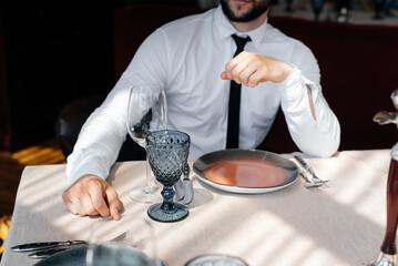 A young bearded male businessman is sitting at a table in a fine restaurant and waiting for his order. Customer service in the catering.