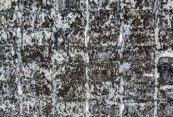 Fototapeta premium Dirty old eroded cracked plaster cement block fence. Concrete block wall. Destroyed crumbling cement mortar texture. Background of wall. Brick texture with scratches and cracks. brick wall background