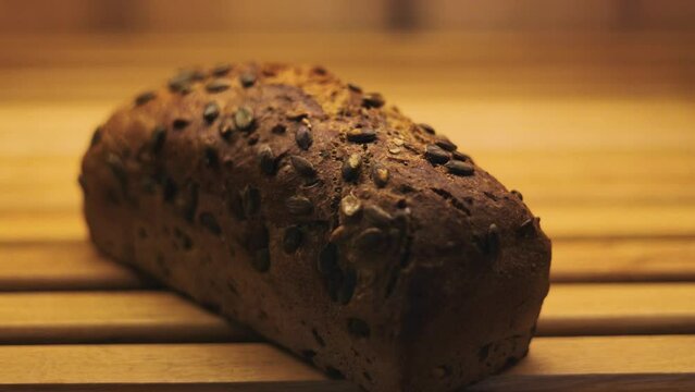 Dolly in of a whole meal bread with pumpkin seeds baked well in a bread oven. Wooden background