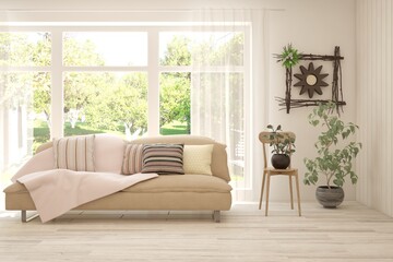 Fototapeta premium White living room with sofa and summer landscape in window. Scandinavian interior design. 3D illustration