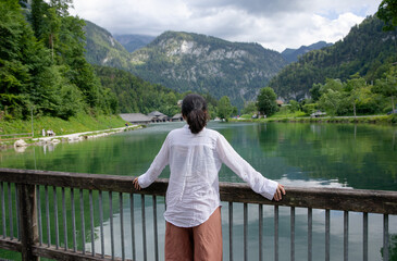 The girl in the white shirt watches a beautiful mountain landscape. The girl, a view of the mountains and the lake. Weekend in nature