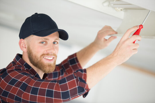 contractor unscrewing overhead ceiling panel