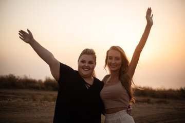 group of friends, plus size with  thin girl spend happy time together and posing in the nature. Beautiful overweight and strong women have fun, enjoy the momet of sunset .