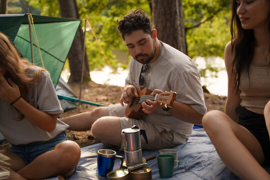 Photo of three friends with food and drink resting on their weekend in forest journey.