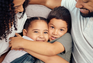 Fototapeta premium Portrait, happy family and children hug and bonding on a sofa, happy and relax with mother and father at home. Smile, relax and embracing kids enjoying a playful day with loving, caring parents