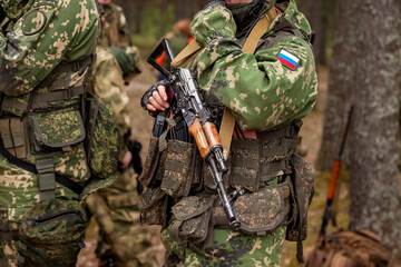 Close up hands russian soldier man dressed military camouflage uniform holds weapon in woodland at...