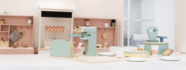 Stylish kid's playing room interior for toddlers. Pastel colorful toy kitchen with wooden kitchen utensils ready for children play