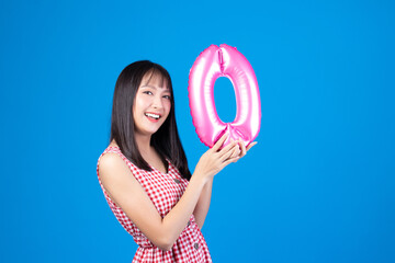 Happy new year and Merry Christmas concept. Beautiful young asian woman with balloons number 0 on blue background.