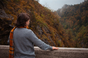 Fototapeta premium man looks up at mountains, lonely, pensive, autumnal landscape, rainy bad cloudy weather, alone. Travel and tourism. misty forest