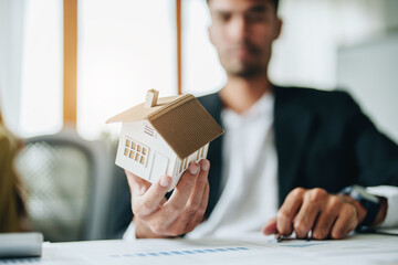portrait of a customer holding a house model shows a lot of thought in managing borrowing risks for homes - obrazy, fototapety, plakaty