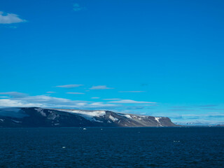 Spectacular panorama view of Wilhelmoya island with mountain range and blue sky. Torellneset, Nordaustlandet  
Spitsbergen, Norway. Tourism and vacations concept.