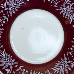 antique dark red porcelain service with national painting. an old plate in the Ukrainian style in a...