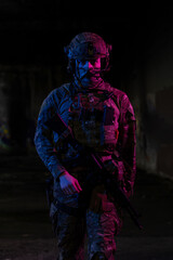 Army soldier in Combat Uniforms with an assault rifle and combat helmet night mission dark...