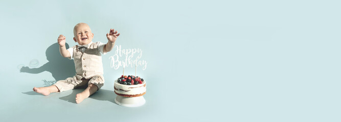 Toddler boy and first healthy homemade birthday cake with berries on blue background. Copy space....