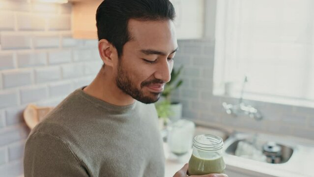 Man drinking a green juice for health, wellness and organic diet in a kitchen at home. Happy guy with healthy, weight loss and natural lifestyle enjoying smoothie for breakfast, energy and nutrition.