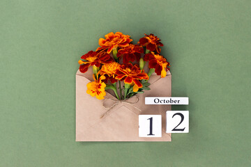 October 12. Bouquet of orange flower in craft envelope and calendar date on green background....