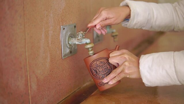 Woman fills a cup of mineral water close-up