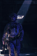Army soldier in Combat Uniforms with an assault rifle and combat helmet night mission dark...