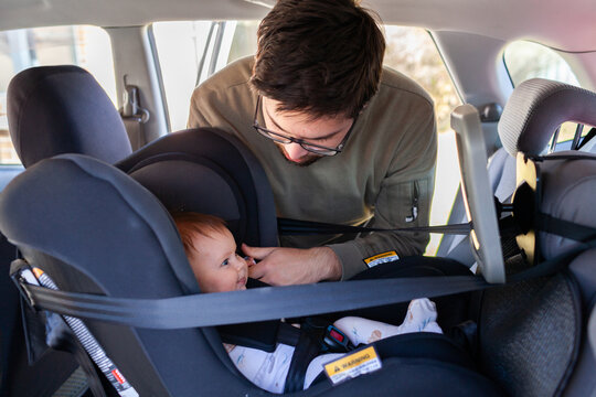 Dad putting baby into rear facing child car seat - clicked in safely