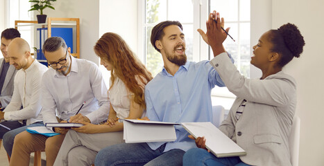 Cheerful colleagues give each other after successfully completed task at business training. People...