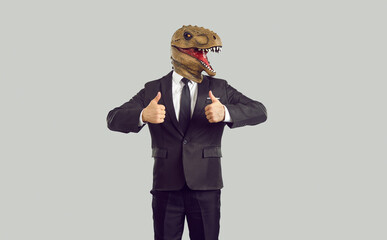 Creative recommendation. Funny businessman in humorous trendy dinosaur mask showing thumbs up on...
