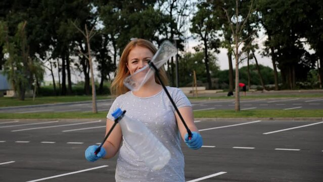 Portrait of a female volunteer with tongs for collecting plastic garbage in her hands. The concept of volunteering and garbage collection. Environmental protection.