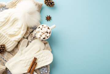 Winter concept. Top view photo of cup of hot drinking with marshmallow white knitted mittens...