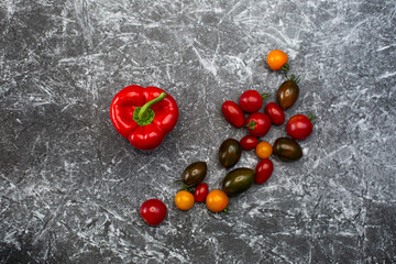 Red paprika peppers on a black and white background next to delta red brown burgundy tomatoes...