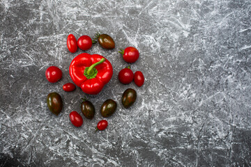 Red paprika peppers on a black and white background next to delta red brown burgundy tomatoes healthy food fresh vegetables bright food vegan background for a menu site in restaurant top view flat lay